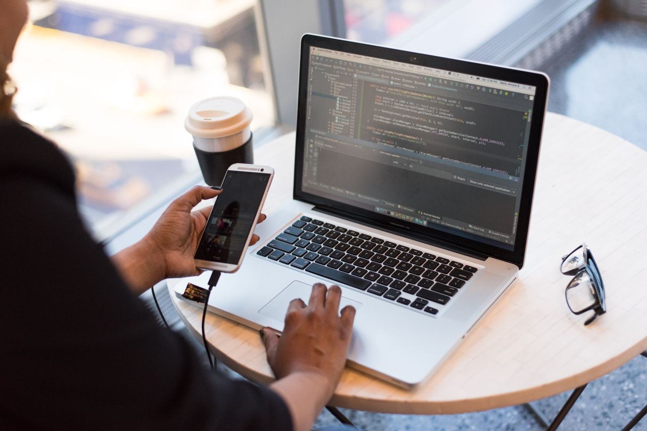 awards-img Developer working remotely, coding on a laptop with phone in hand, showcasing modern work culture.
